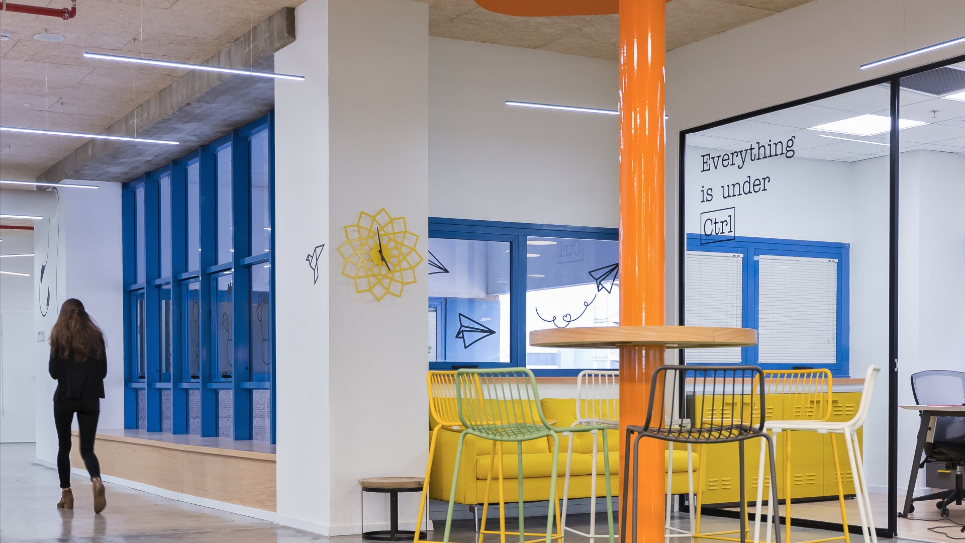 Bright hallway and seating area at Foto Master with colorful chairs, blue windows, and “Everything is under Ctrl” wall text.