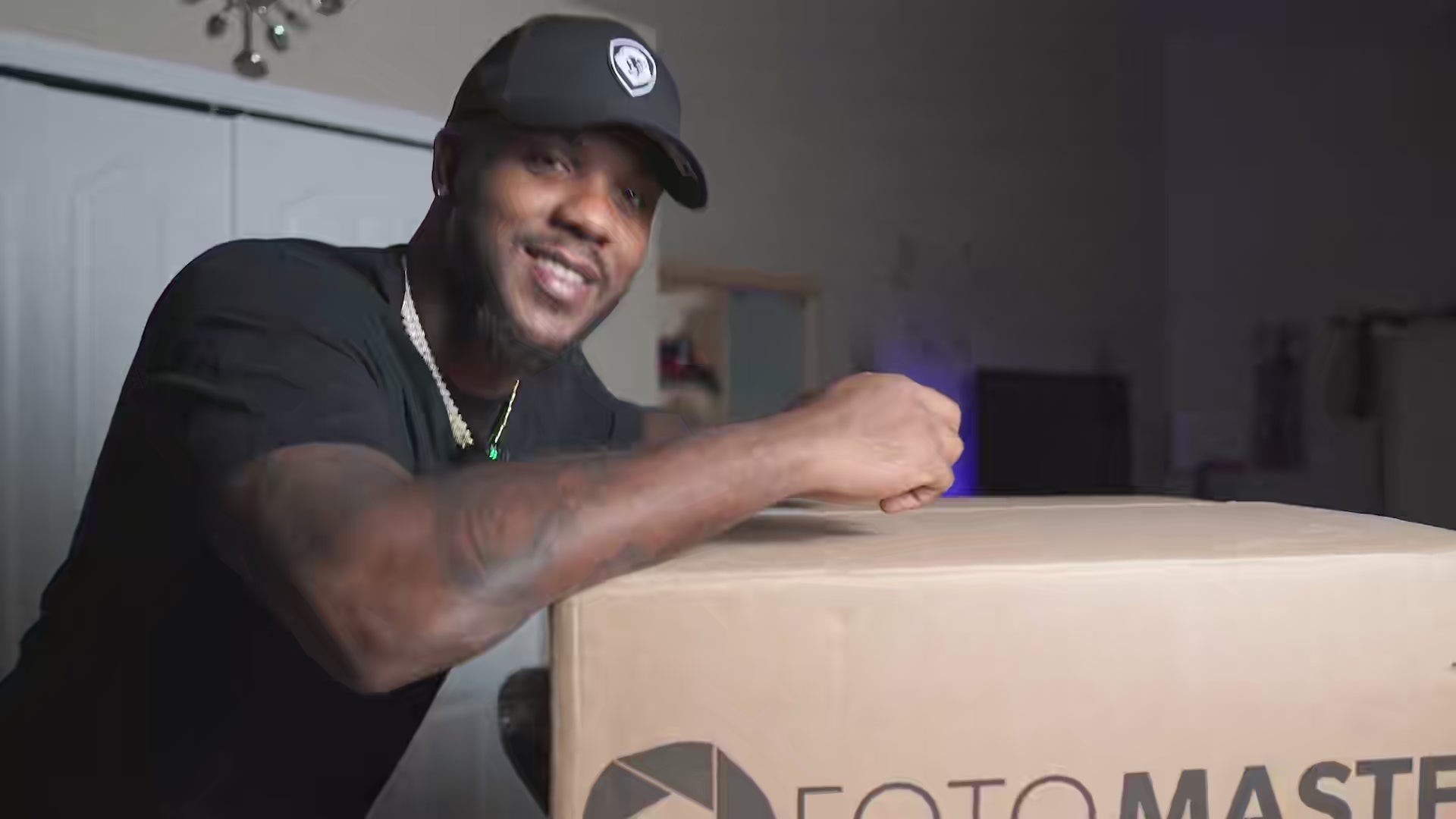 Smiling man in cap (Andre Lewis) of 360andbeyond posing with a Foto Master box during a photo booth testimonial video.