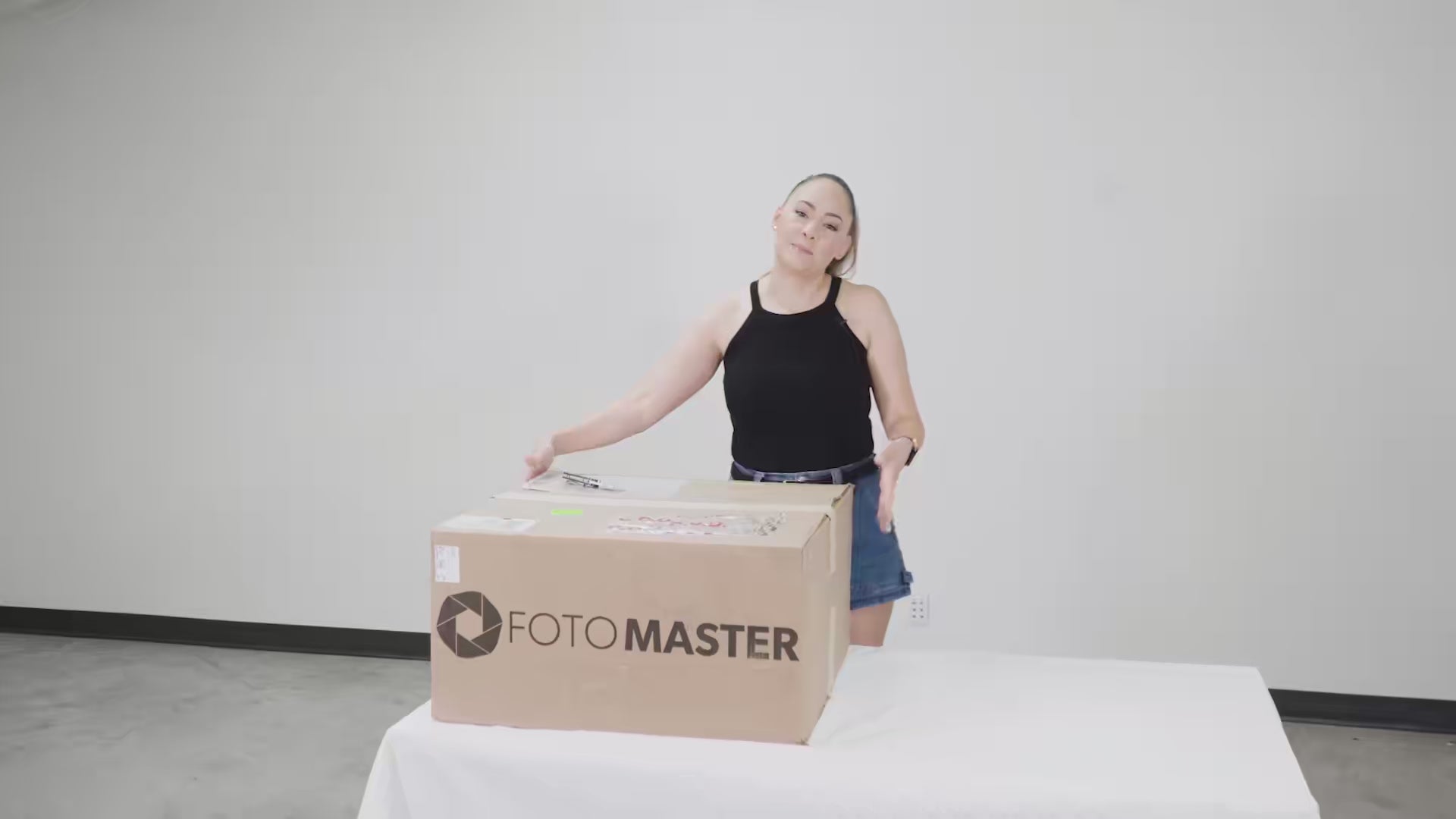 Smiling woman in ponytail of Photo Booth Mastery posing with Foto Master box in a photo booth testimonial.